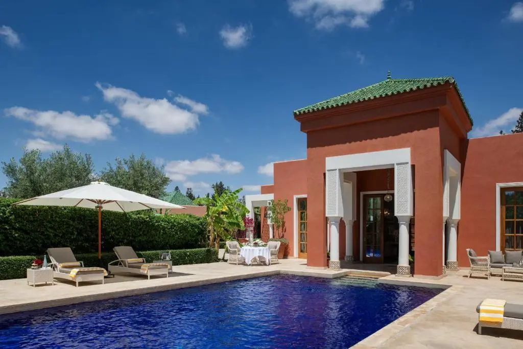 Außenbereich einer Villa mit privatem Pool, Sonnenliegen und Terrasse unter blauem Himmel.