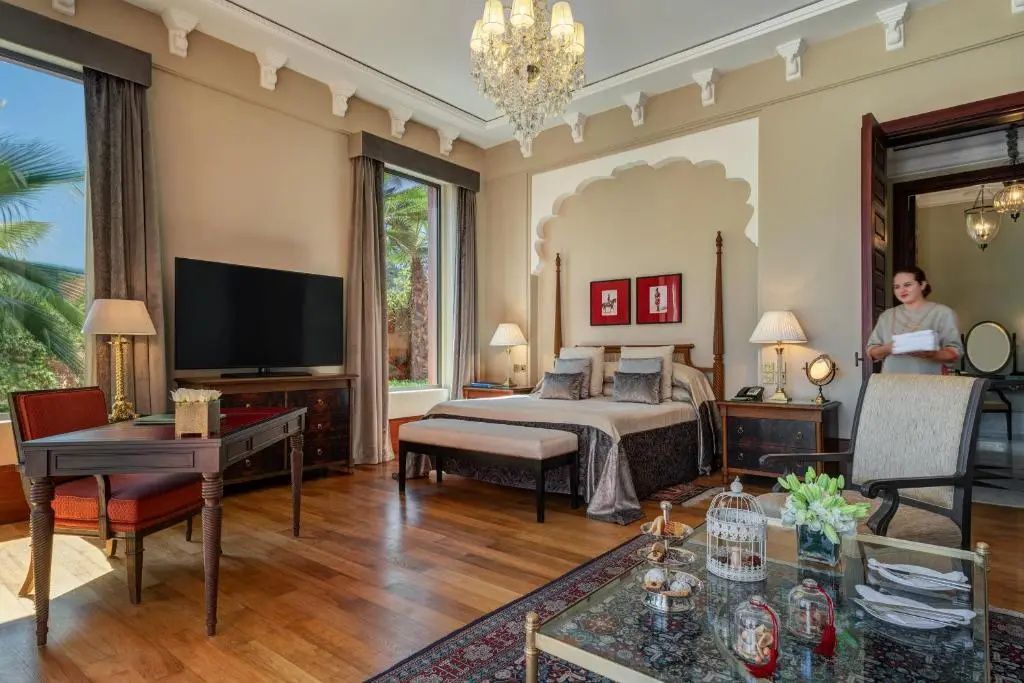 Schlafzimmer mit großem Doppelbett, Parkettboden, Fernseher und Blick in den Garten durch ein großes Fenster.