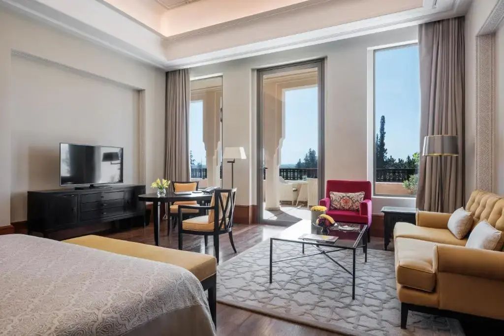 Wohnbereich der Suite mit Schreibtisch, rotem Sessel und Blick auf die Terrasse.