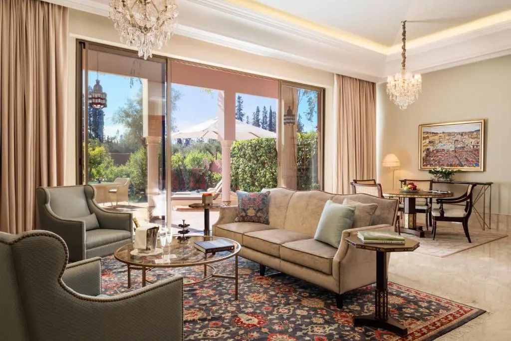 Elegantes Wohnzimmer mit beigem Sofa, Teppich und breiter Glasfront zur Terrasse mit Garten.