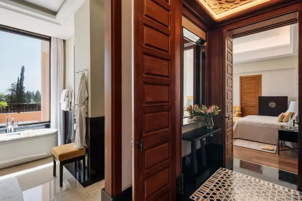 Eingangsbereich der Suite mit Holztüren, Spiegel und Blick in das Badezimmer.