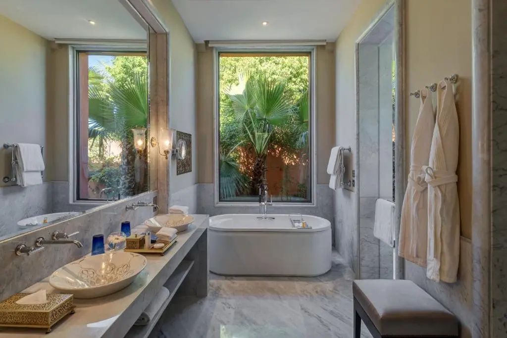 Badezimmer mit frei stehender Badewanne, doppeltem Waschtisch und großem Fenster zum Garten.