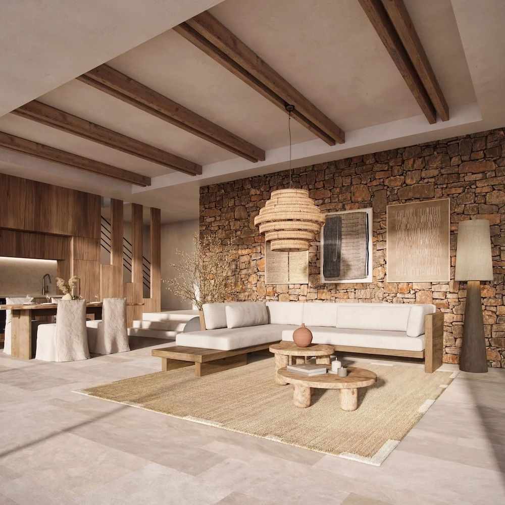 Wohnbereich einer Suite mit Wand aus Naturstein, beigefarbener Couch und Holzbalken an der Decke