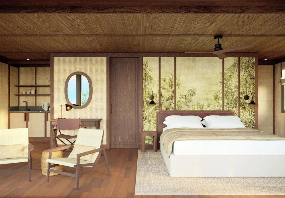 Schlafzimmer mit Doppelbett, hellem Teppich, Holzdecke, Sessel und Schreibtisch.
