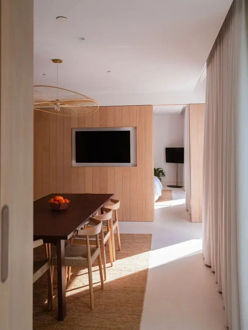 Essbereich im Hotelzimmer mit großem Esstisch, Stühlen und Fernseher an der Wand.