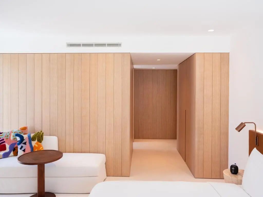 Moderne Raumgestaltung im Hotelzimmer mit hellem Holz und schlichter Wandverkleidung.