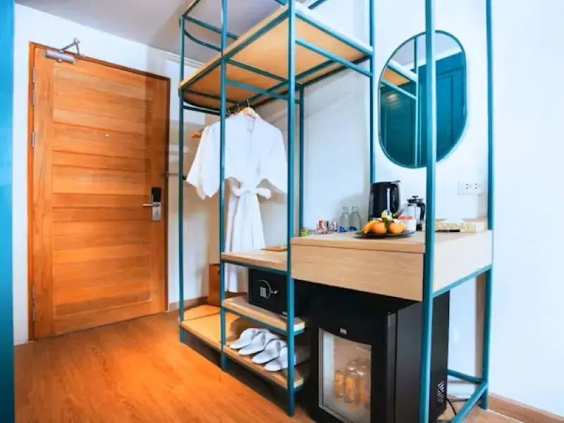 Offenes Regalsystem aus blauem Metall mit Bademantel, Minibar und Wandspiegel.