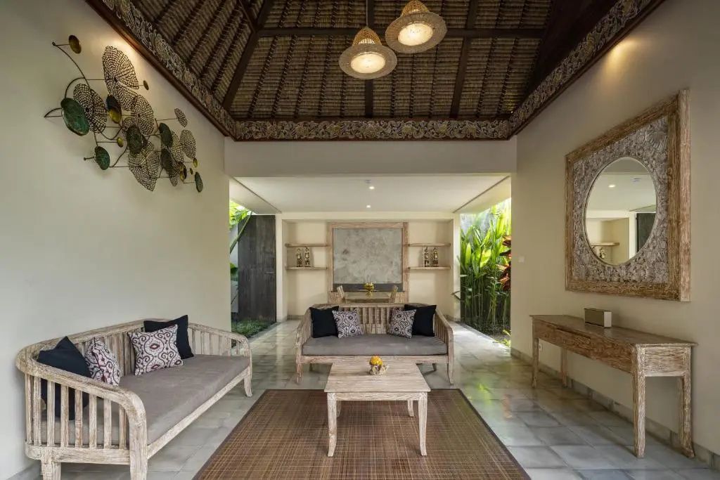 Offener Sitzbereich einer Villa mit Holzmöbeln, Webenmatte und hoher Decke im traditionellen Stil.