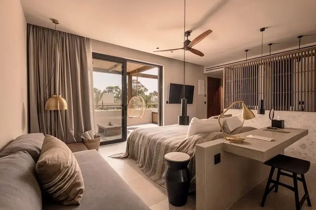Modernes Schlafzimmer einer Suite mit Doppelbett, Deckenventilator und Balkonzugang.