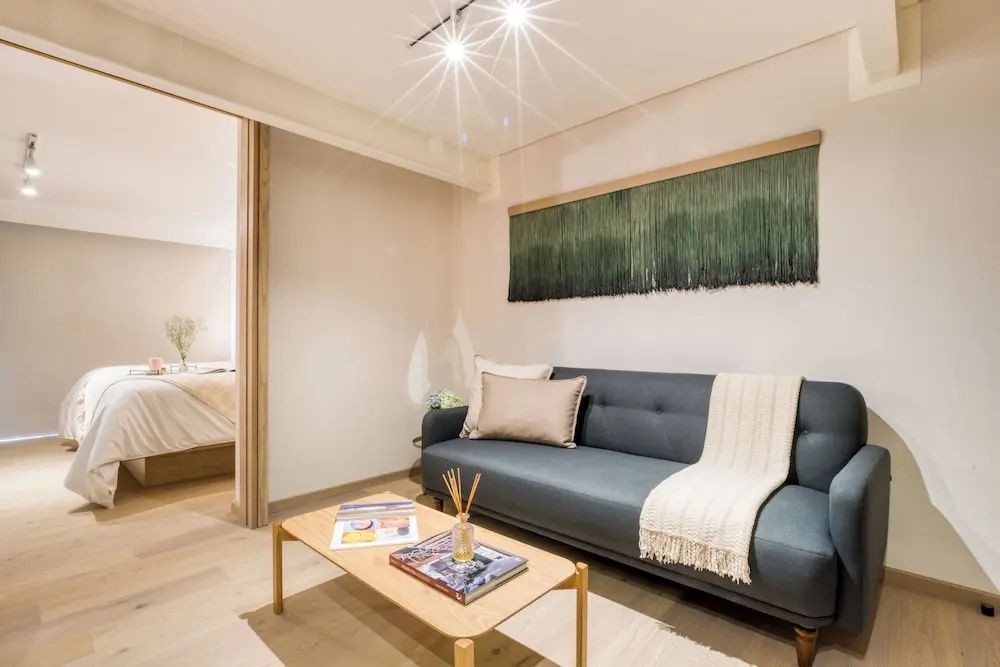 Wohnbereich einer Suite mit dunklem Sofa, hellem Holztisch und Wanddekoration.