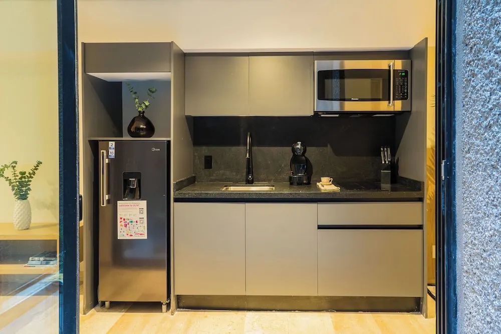 Graue Küchenzeile mit Spülbecken, Mikrowelle, Kaffeemaschine und Kühlschrank
