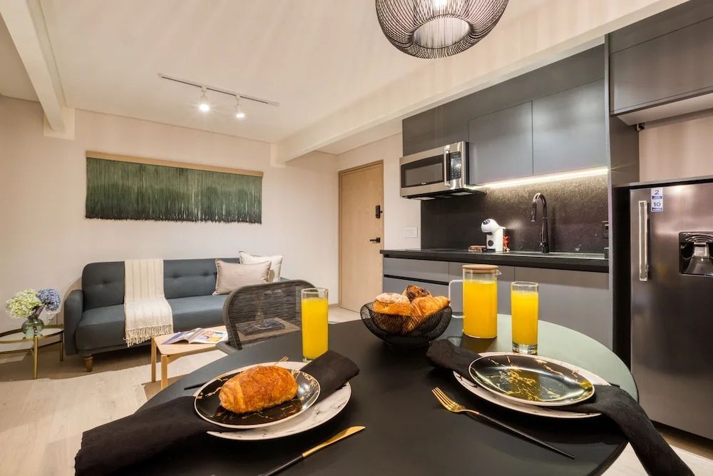 Essbereich und Küchenzeile eines Apartments mit gedecktem Tisch im Vordergrund.