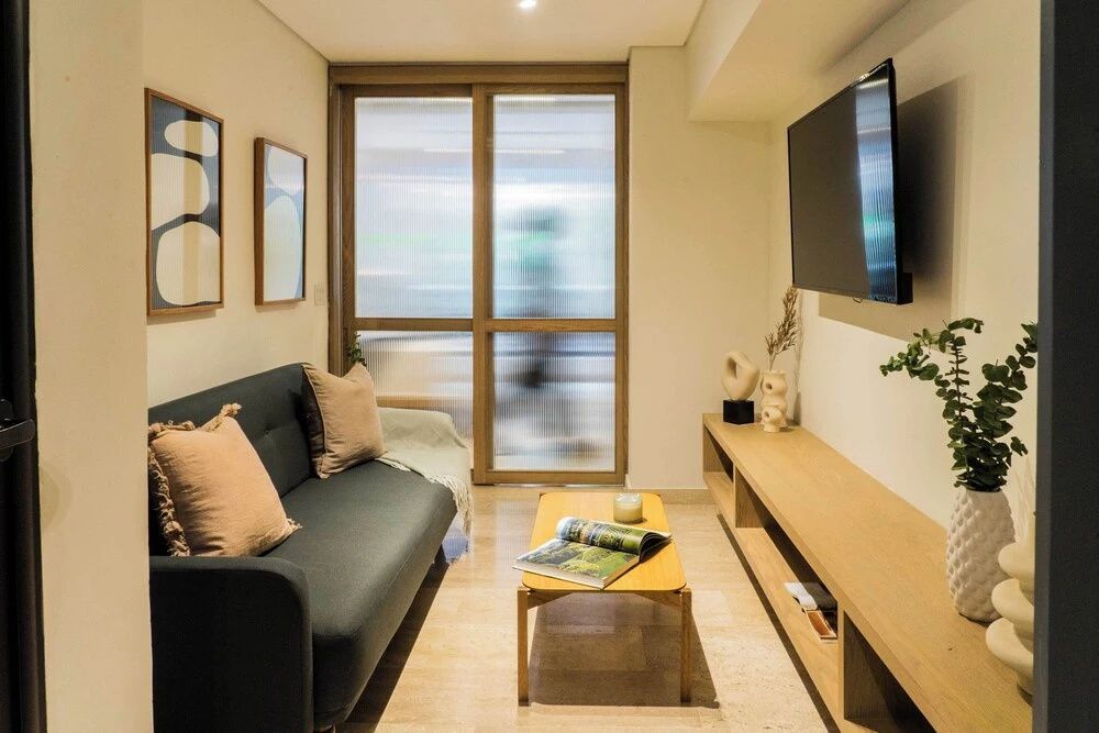 Sitzbereich im Wohnzimmer mit dunkelgrünem Sofa, Couchtisch und Wandfernseher