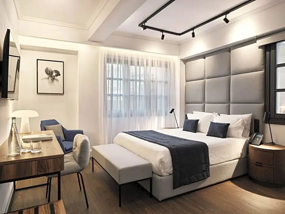 Modernes Hotelzimmer mit großem Doppelbett, gepolsterter Kopfteilwand und Schreibtisch.