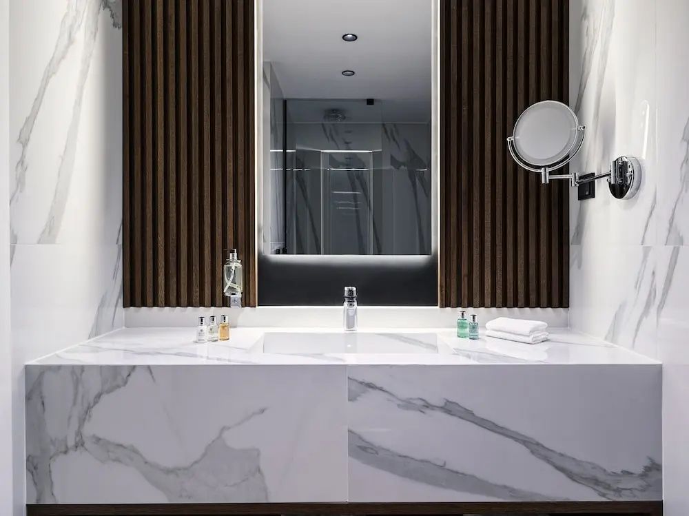 Badezimmerbereich mit hellem Marmorwaschtisch und dunklen Holzlamellen an der Wand.