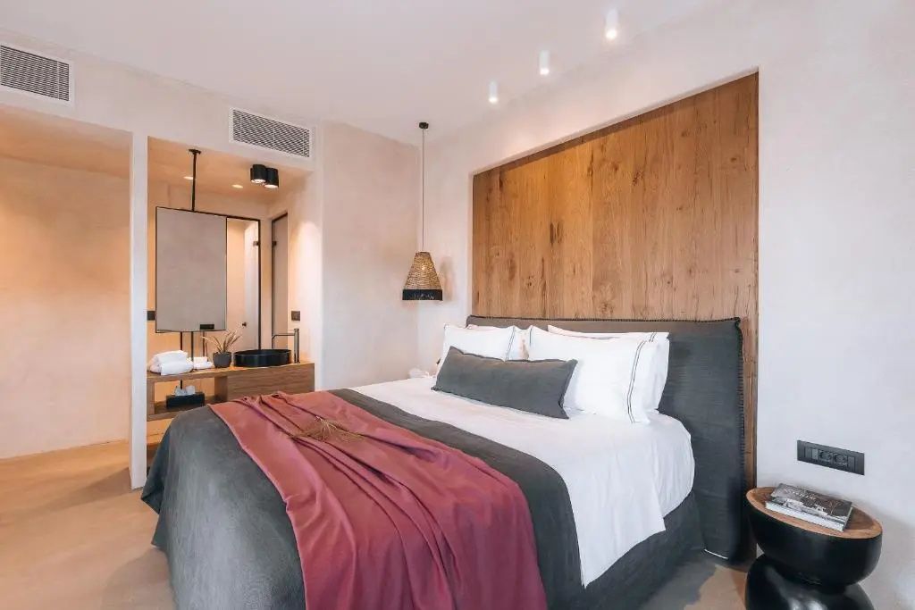 Doppelbett mit Holzvertäfelung an der Wand und offenem Badezimmerbereich