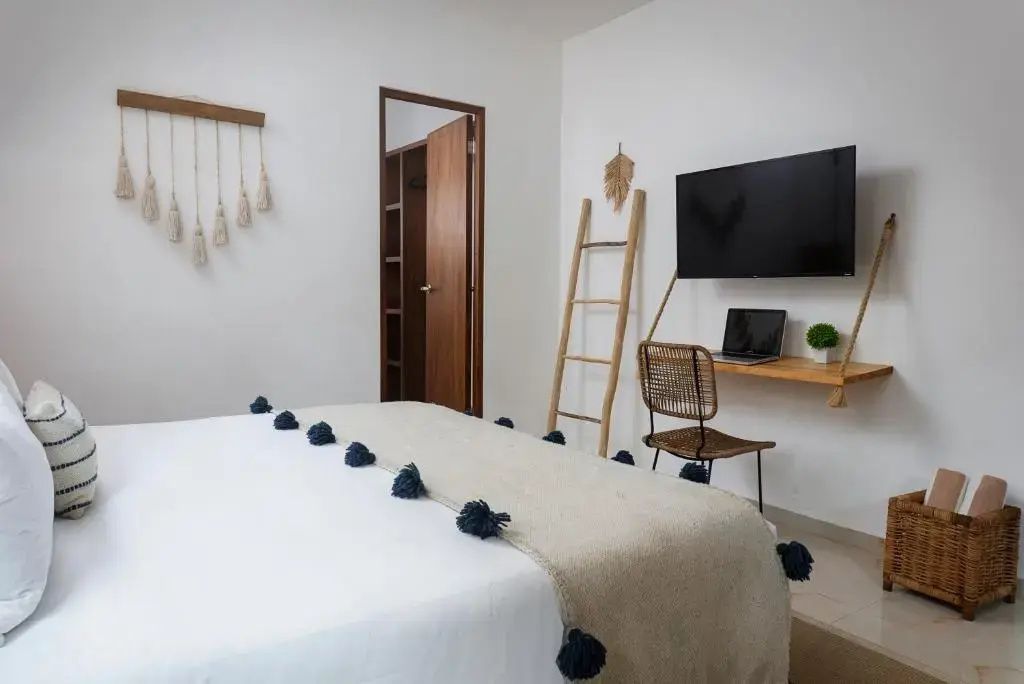 Arbeitsbereich im Zimmer mit Wand TV, Holzschreibtisch, Stuhl und einer Dekoleiter.