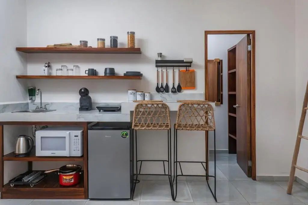 Voll ausgestattete Küchenzeile mit Minikühlschrank, Mikrowelle und zwei Barstühlen.