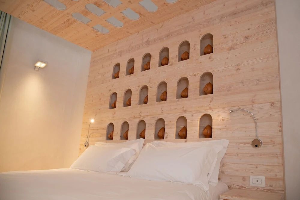 Doppelbett mit weißer Bettwäsche unter einer hölzernen Deckenkonstruktion und Wandverkleidung.
