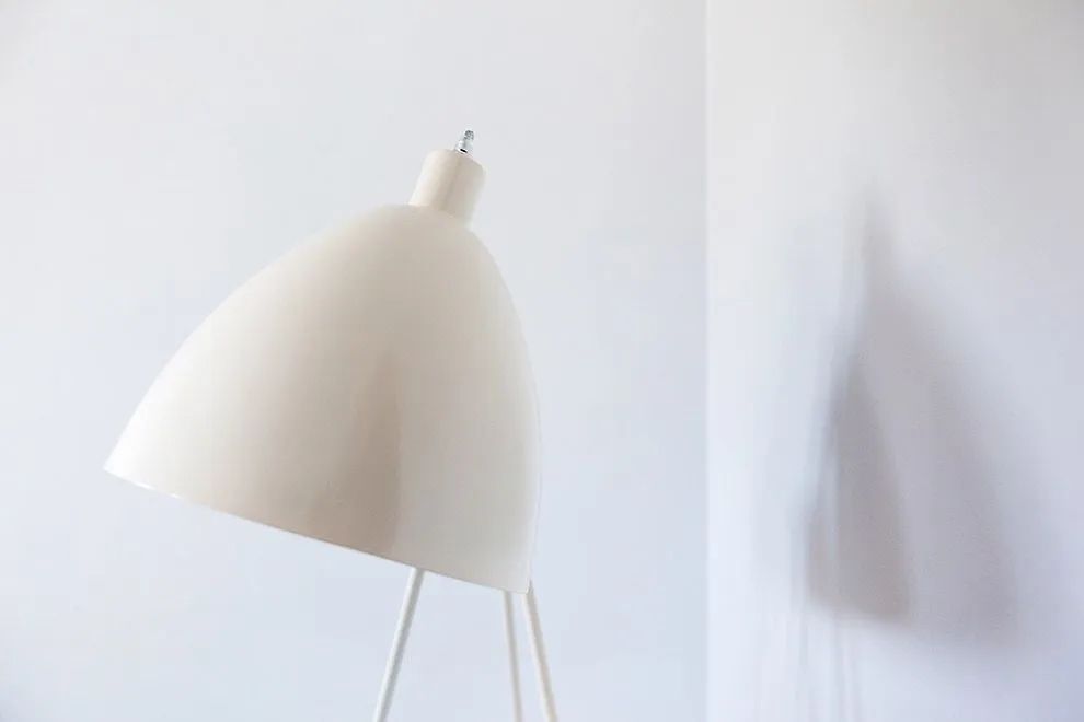 Nahaufnahme einer schlichten weißen Lampe vor einer hellen Wand.