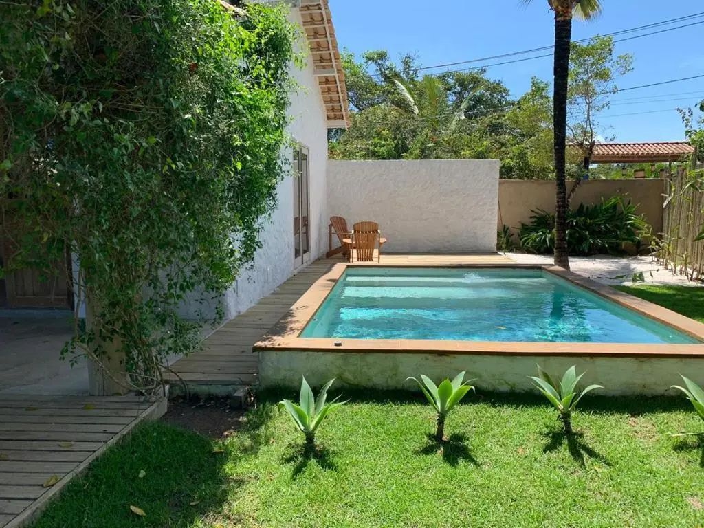 Kleines Poolbecken auf einer Holzterrasse im Garten neben der Außenwand der Unterkunft.