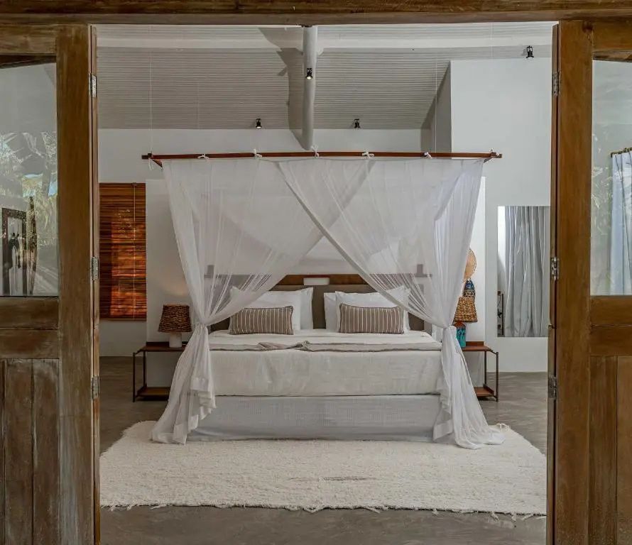 Blick durch die Tür auf ein helles Schlafzimmer mit überdachtem Doppelbett.
