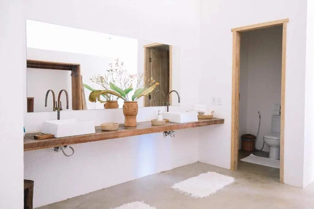 Badezimmer mit doppelter Waschkonsole aus Holz, zwei Waschbecken und großem Spiegel.