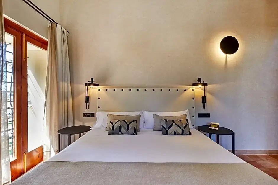 Doppelbett mit gepolstertem Kopfteil, Leselampen und Dekokissen im Hotelzimmer.