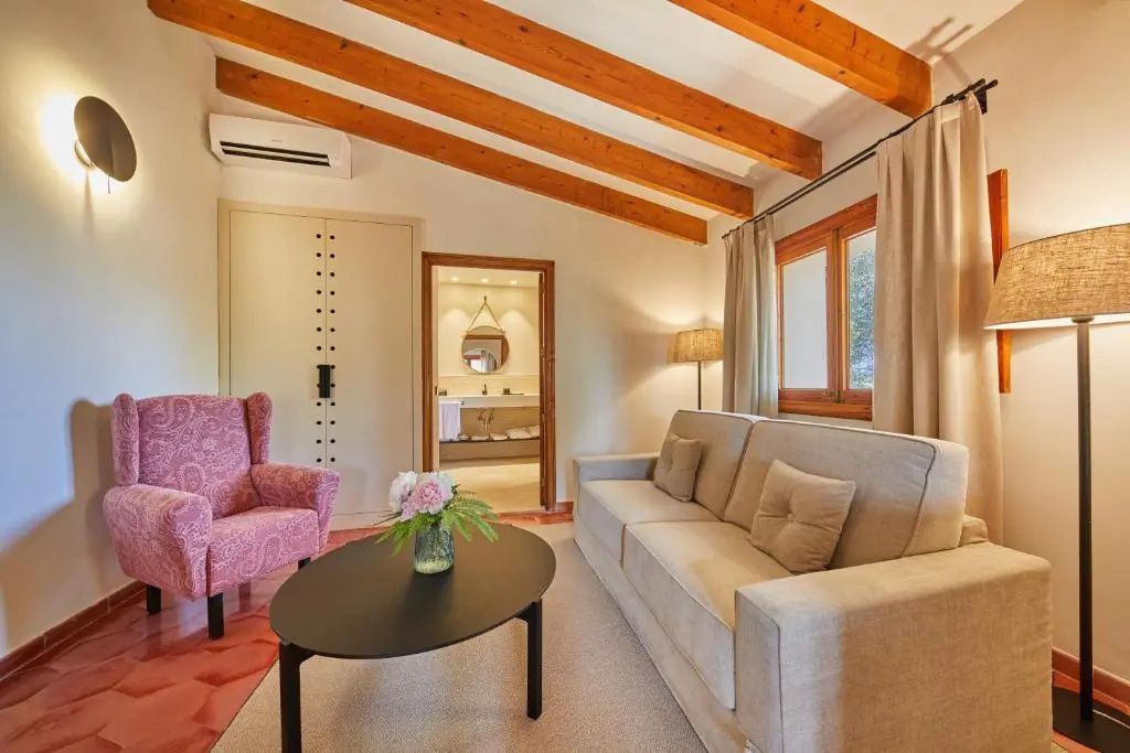 Sitzbereich mit hellem Sofa, rosa Sessel und Couchtisch vor dem Badzugang.