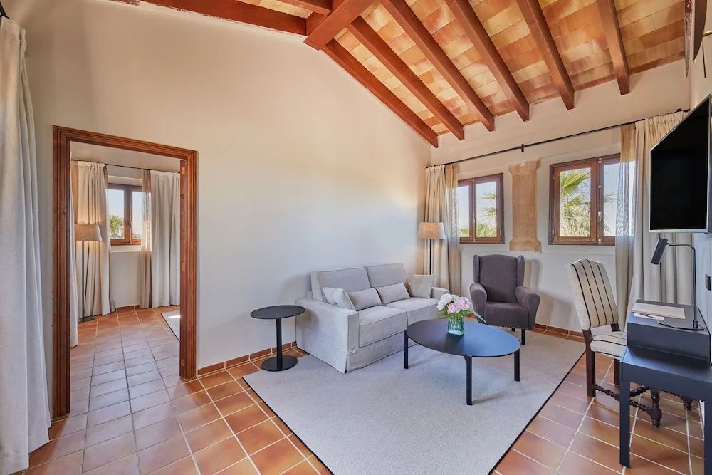 Gemütliche Sitzecke mit grauem Sofa, Sessel und Couchtisch auf einem hellen Teppich.