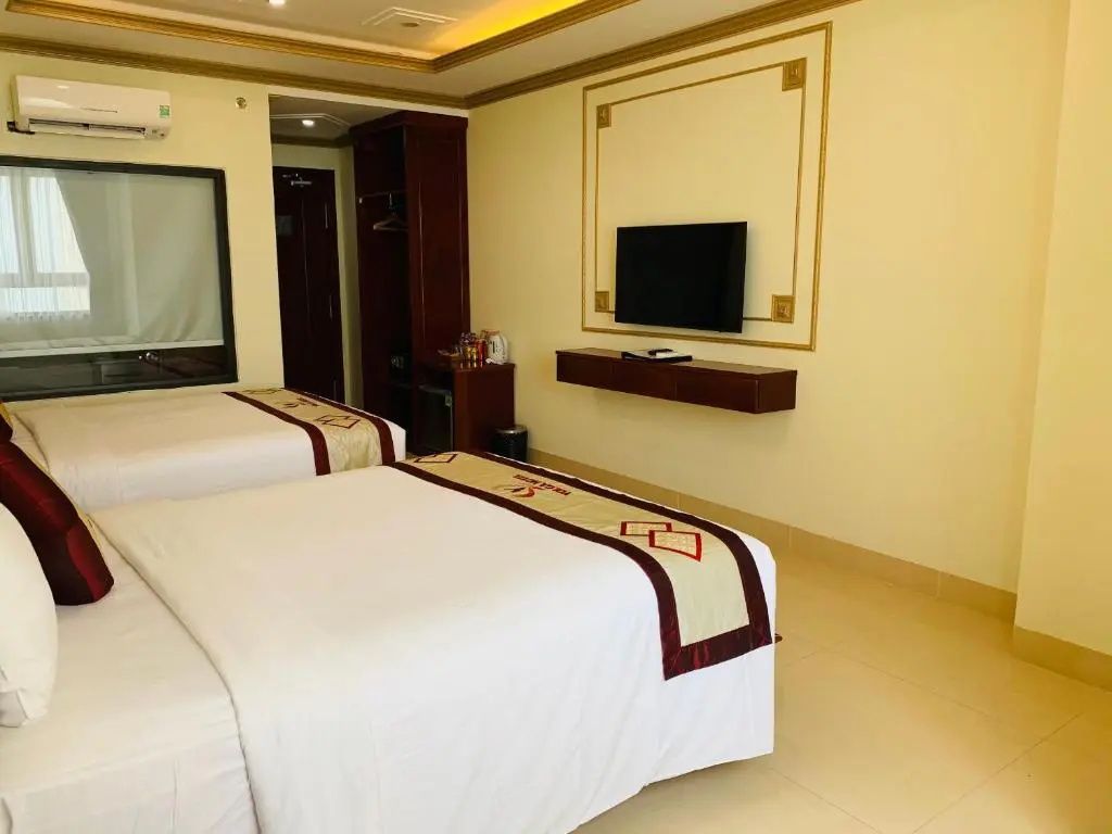 Blick auf den Flachbild-TV an der Wand und die Betten in einem geräumigen Hotelzimmer.