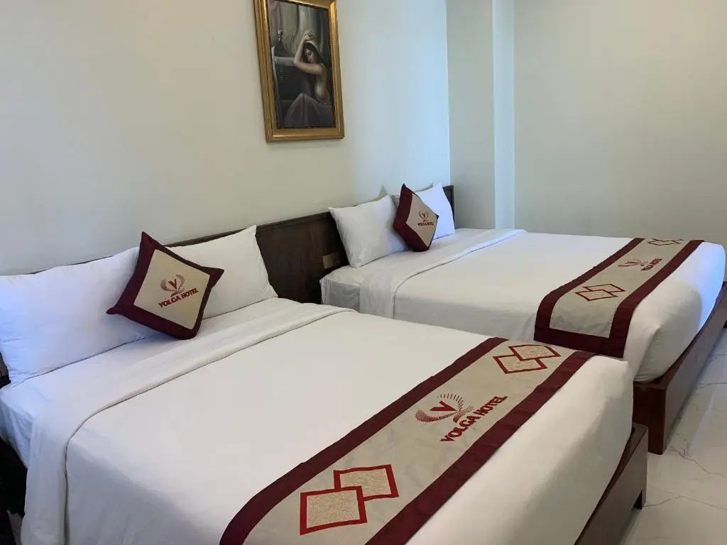 Detailansicht von zwei Betten mit Zierkissen und bestickten Bettläufern im Hotelzimmer.