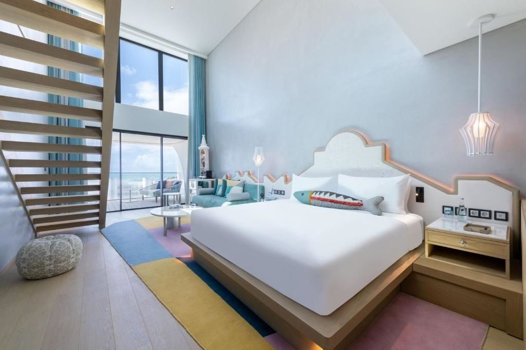Doppelbett mit Zierkissen in einem hellen Zimmer mit hoher Decke und Galerie.
