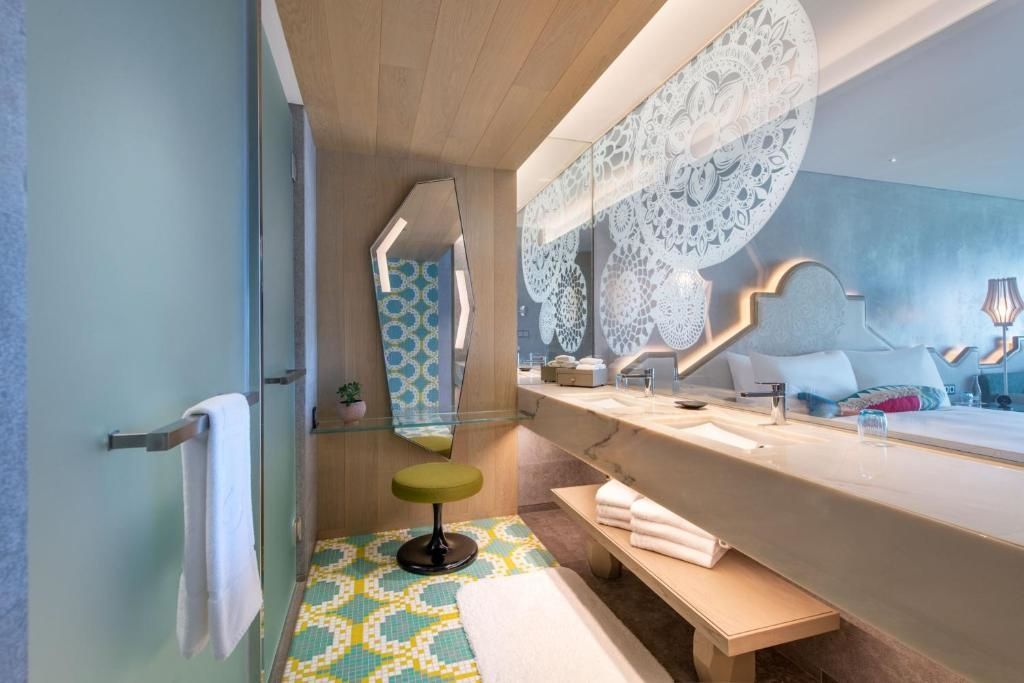 Badezimmer mit Doppelwaschbecken, auffälligen Fliesen und großem Spiegel.