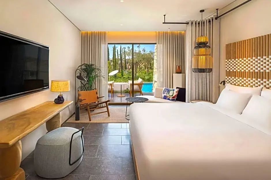 Modernes Hotelzimmer mit Doppelbett, Sitzbereich und Terrasse mit Blick auf den eigenen Pool.