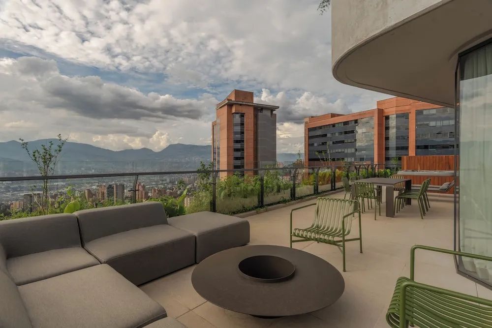 Dachterrasse mit grauen Loungemöbeln und Ausblick auf die Stadt und Berge.