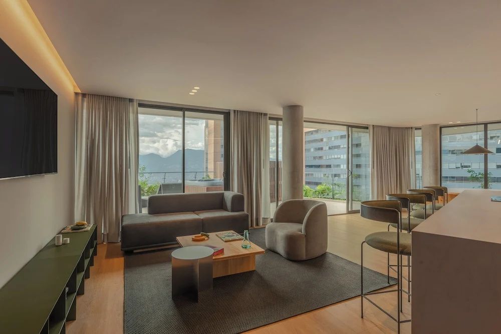 Geräumiger Wohnbereich mit modernem Sessel, Sofa und Zugang zur Terrasse.