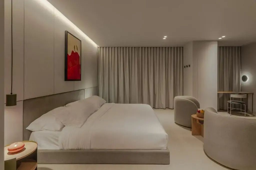 Modernes Hotelzimmer mit großem Doppelbett, indirekter Beleuchtung und Wandbild.