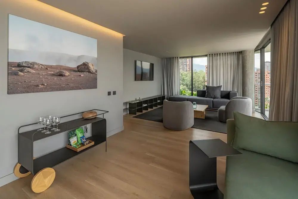 Großzügiger Wohnraum einer Suite mit Holzboden, Sitzgelegenheiten und Wandbild.