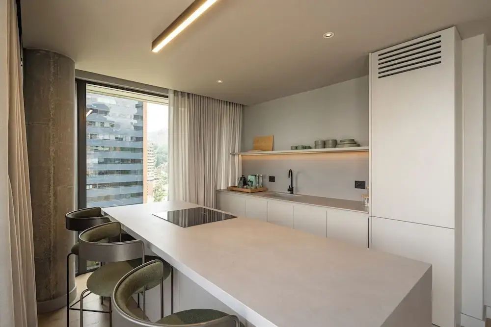 Moderne Küchenzeile mit Kochinsel, Spüle und Stühlen im Hotelapartment.