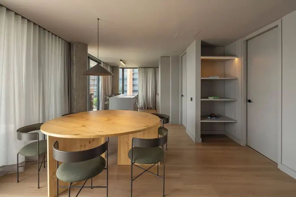 Moderner Essbereich mit rundem Holztisch und Stühlen in einem hellen Zimmer.