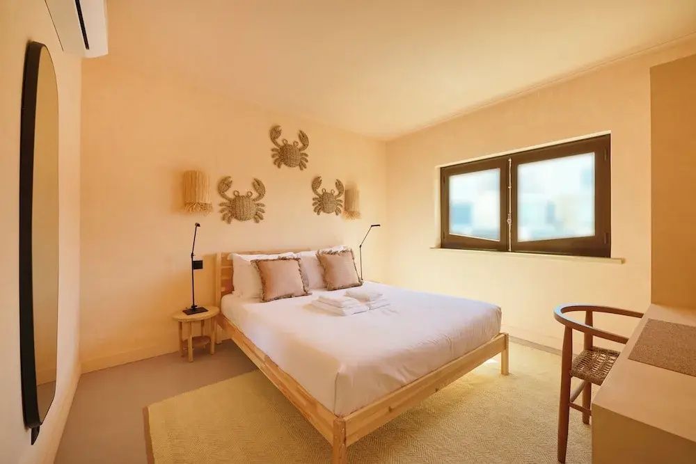 Hell eingerichtetes Schlafzimmer mit Doppelbett aus Holz und Krabben an der Wand.
