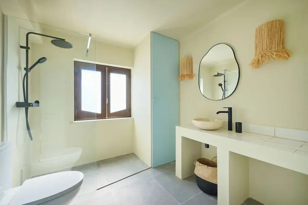 Modernes Badezimmer mit Waschtisch, organisch geformtem Spiegel und begehbarer Dusche.
