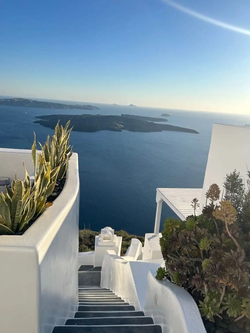 Weiße Architektur mit bepflanzten Steinbeeten und Blick auf das weitläufige Meer.