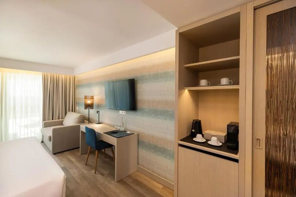 Modernes Hotelzimmer mit Schreibtisch, Fernseher an der Wand und Kaffeestation.