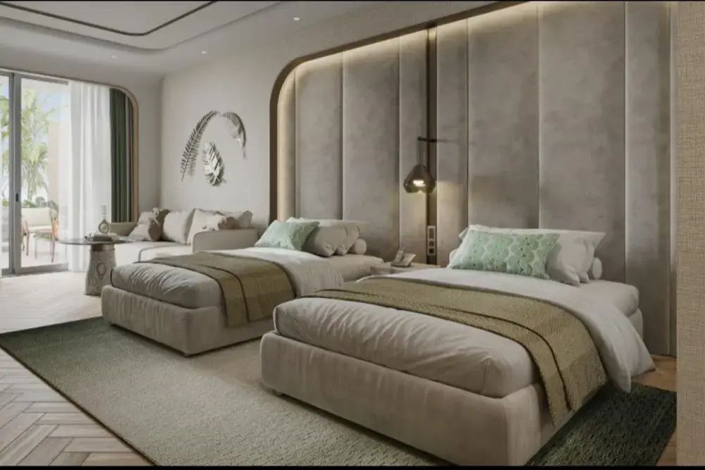 Zwei Einzelbetten mit beigen Tagesdecken und gepolsterter Wandverkleidung im Hotelzimmer.