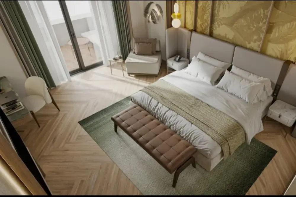 Doppelbett mit brauner Sitzbank, Sessel und Balkonzugang im Hotelzimmer aus der Vogelperspektive.