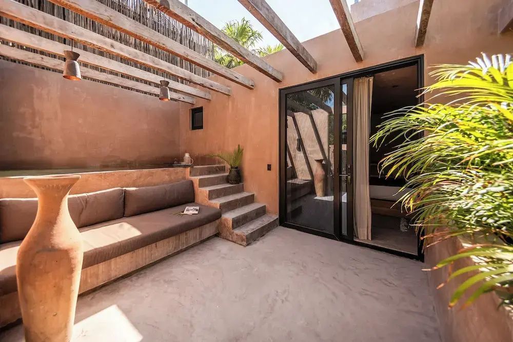 Sonnige Terrasse mit gemauerter Sitzbank, Steintreppe und hölzerner Pergola.