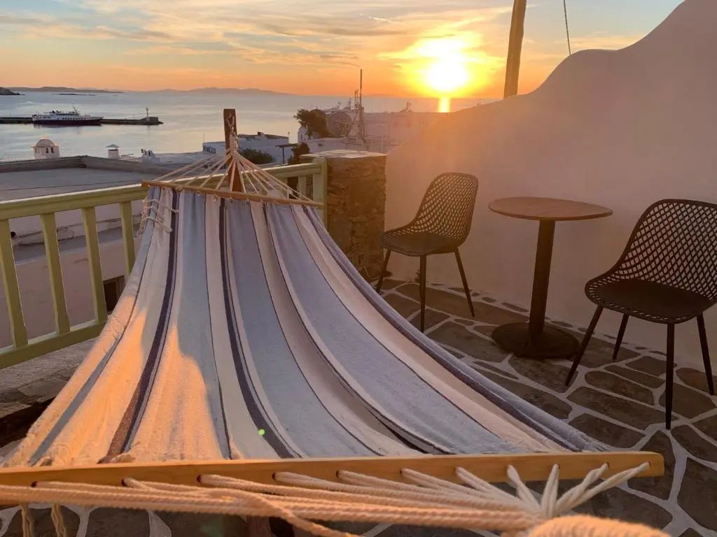 Terrasse mit Hängematte, kleinen Stühlen und Blick auf den Sonnenuntergang über dem Meer.