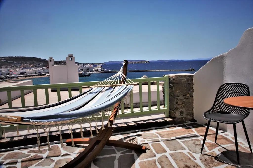 Balkon mit Steinboden und einer Hängematte mit freiem Blick auf das Meer und den Hafen.